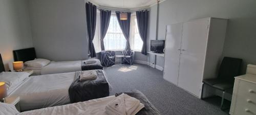 a hotel room with three beds and a television at Royal Pier in Sandown