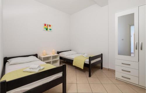 a bedroom with two beds and a dresser and a mirror at Awesome Apartment In Lukovo Sugarje With 2 Bedrooms And Wifi in Pavičići