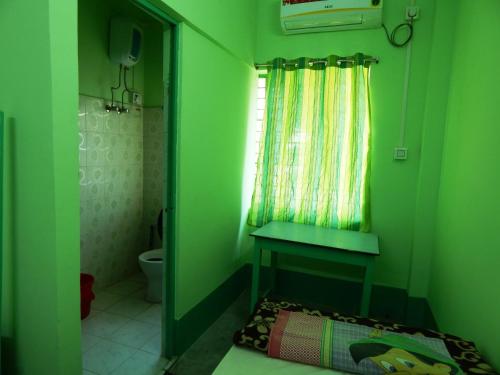 a green bathroom with a toilet and a window at Seva Kendra Hijli Kharagpur in Kharagpur