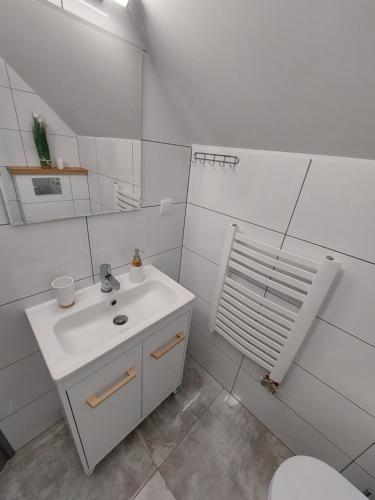 La salle de bains blanche est pourvue d'un lavabo et de toilettes. dans l'établissement Pokój studio z balkonem, à Grywałd