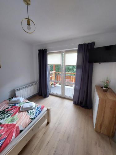 a bedroom with a bed and a large window at Pokój studio z balkonem in Grywałd