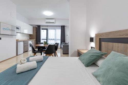 a bedroom with a large white bed and a kitchen at Travel Habitat La Marina Real in Valencia