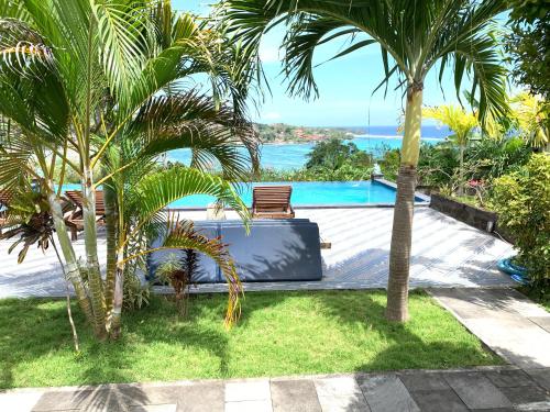 a resort with a pool and two palm trees at Bukit Permata Lembongan in Nusa Lembongan