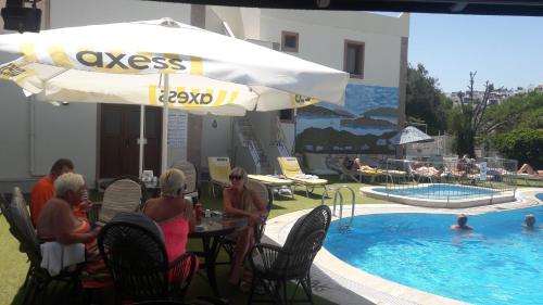 a group of people sitting at a table next to a pool at Ozukara Apart 1 in Gümbet