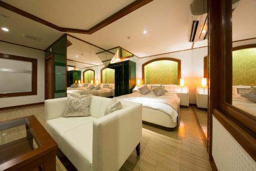 Habitación de hotel con 2 camas y sofá en ホテル　ミロワール en Hirakata