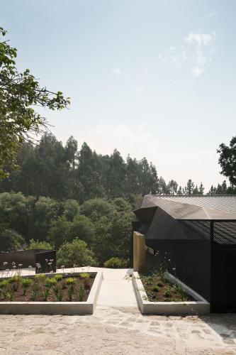 a building with a black roof and some plants at Pazo da Buzaca in Moraña