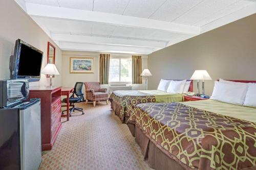 a hotel room with two beds and a flat screen tv at Travelodge by Wyndham Iowa City in Iowa City
