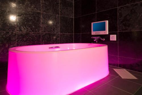 a pink tub in a bathroom with a tv on the wall at ホテル　ミロワール in Hirakata