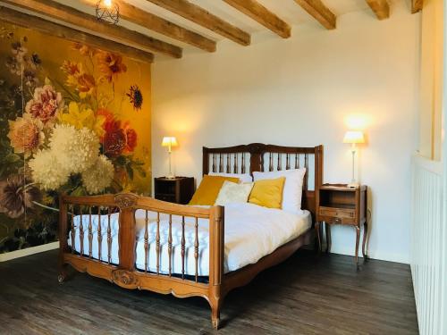 1 dormitorio con 1 cama y una pintura en la pared en Coeur de Roses, gîte & chambre d'hôtes en Alaigne