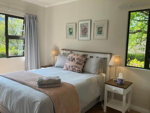 a bedroom with a bed and two windows at Peartree Cottage in Hogsback