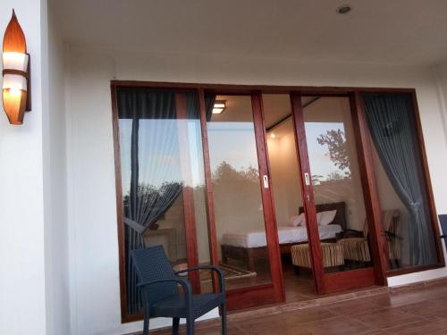 a room with glass doors and a chair and a bed at The luxe villas lombok in Kuta Lombok