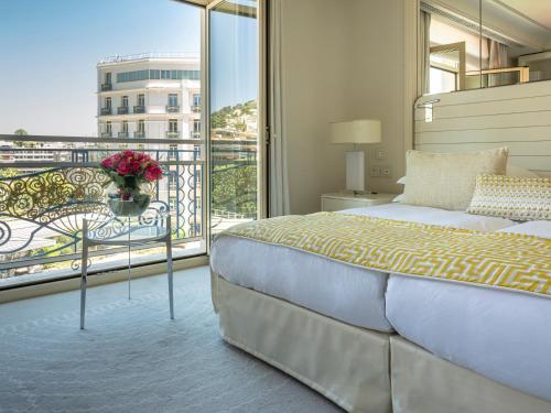 a bedroom with a bed and a balcony with a view at Hôtel Martinez, in The Unbound Collection by Hyatt in Cannes