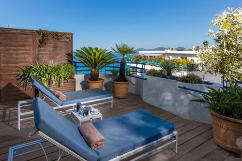 a patio with two blue couches and a table at Hôtel Martinez, in The Unbound Collection by Hyatt in Cannes