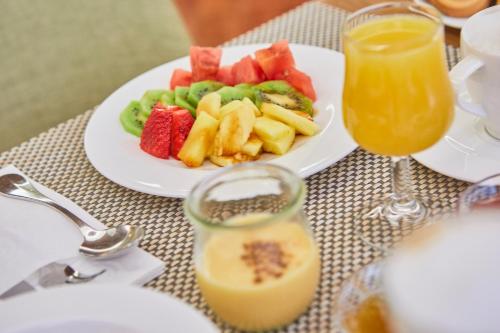 a table with a plate of fruit and a glass of orange juice at Bordoy Continental Palma in Palma de Mallorca