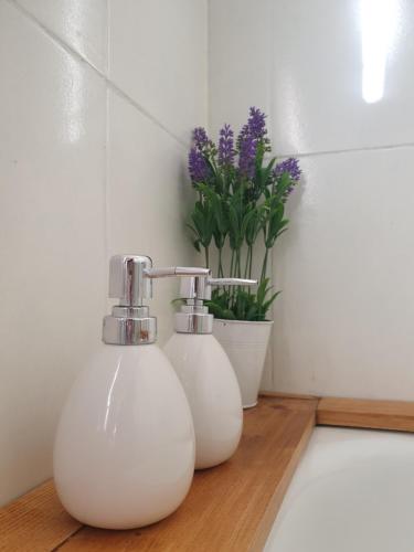 deux vases blancs assis sur un comptoir avec des fleurs violettes dans l'établissement Apartamento Sabugo, à Avilés
