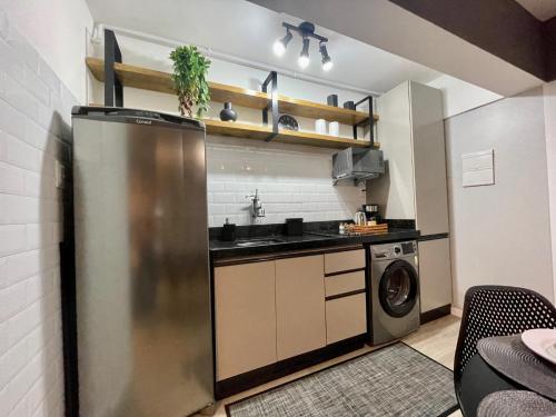 eine Küche mit einem Kühlschrank aus Edelstahl und einem Geschirrspüler in der Unterkunft Studio 308 no Kobrasol à 7km de Floripa in São José