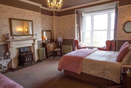 een slaapkamer met een bed, een open haard en een raam bij Penrose Bed & Breakfast in Lostwithiel