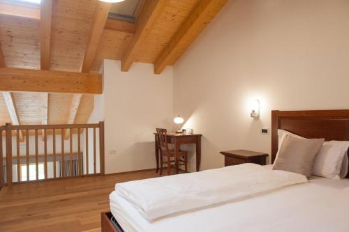 una camera da letto con un grande letto bianco e soffitti in legno di Hotel & Restaurant Pahor a Doberdò del Lago