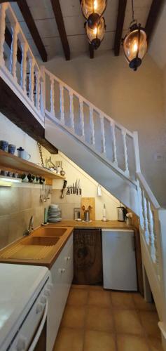 een keuken met een wastafel en een trap bij Le Fier Paon 