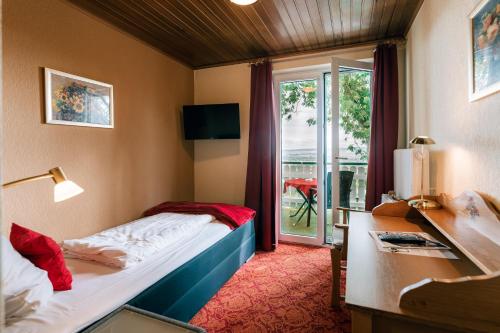 a hotel room with a bed and a desk and a window at Hotel Hasenjäger in Einbeck