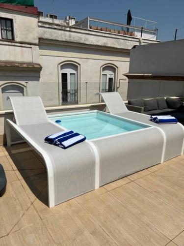 セビリアにあるHommyhome Arenal Luxuryの椅子2脚付きの建物の最上階のプール