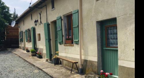 ein Gebäude mit grünen Türen und einer Bank auf einer Straße in der Unterkunft Tiny Acorns chambre d’hôte in Darnac