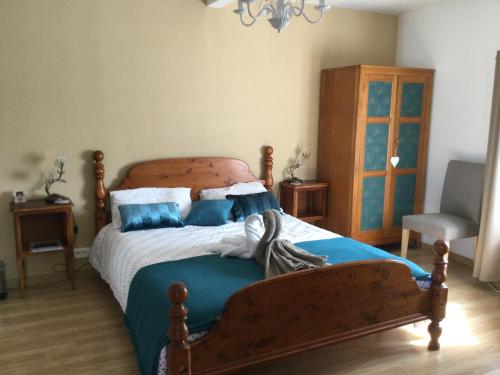 ein Schlafzimmer mit einem Holzbett mit blauen Kissen in der Unterkunft Tiny Acorns chambre d’hôte in Darnac