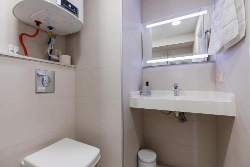 a bathroom with a sink and a toilet and a mirror at The SPOT apartments - Orbi Beach Tower in Batumi