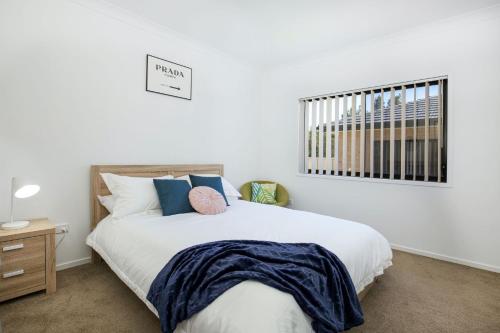 ein Schlafzimmer mit einem großen weißen Bett mit blauen Kissen in der Unterkunft Villa Mare I 4 Mins to Beach in Culburra Beach