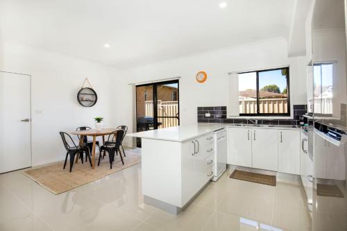 a kitchen with white cabinets and a table with chairs at Villa Mare I 4 Mins to Beach in Culburra Beach