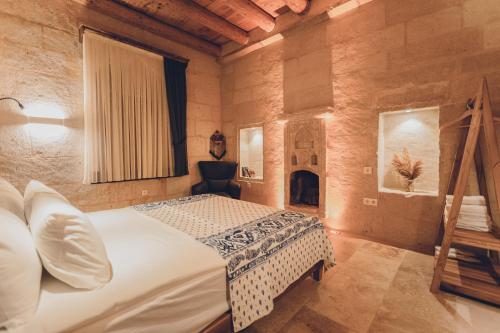 een slaapkamer met een bed en een open haard bij La maison de Şişik in Uchisar
