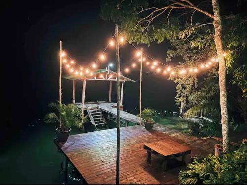 a wooden deck with lights and a wooden bench at La Cabaña de Andre in Nimá
