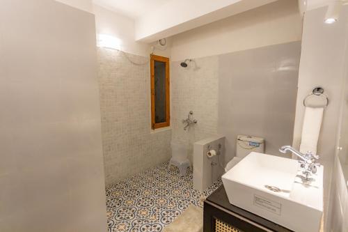 a white bathroom with a sink and a toilet at Seclude Shimla, Taraview in Shimla