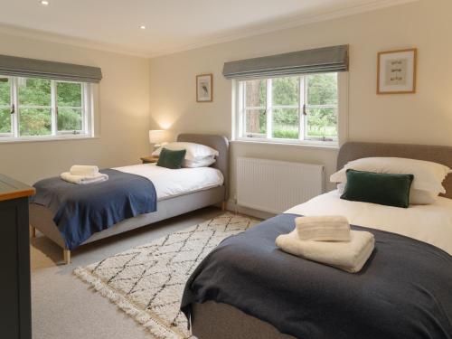 1 Schlafzimmer mit 2 Betten und 2 Fenstern in der Unterkunft The Walled Garden at Woodhall Estate in Hertford