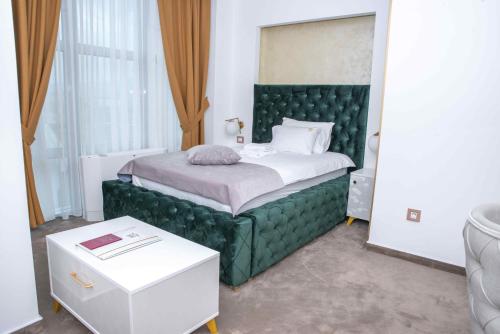 a bedroom with a bed with a green headboard at Hotel IDEAL Deluxe in Novi Pazar