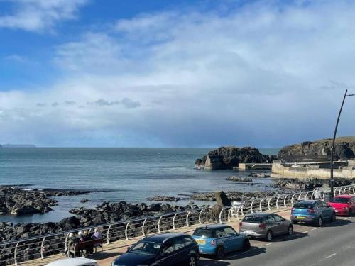 a group of cars parked on a road near the ocean at The Cranny, Portstewart in Portstewart