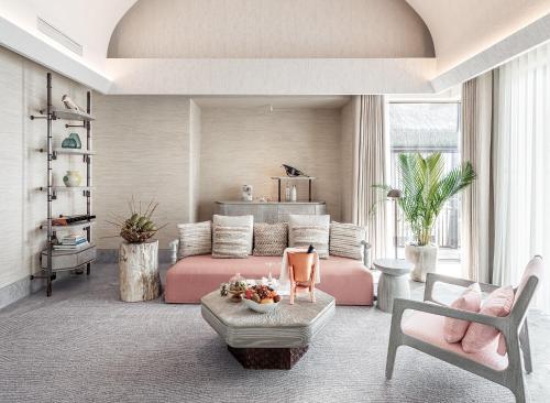 a living room with a pink bed and chairs at JOALI BEING in Raa Atoll