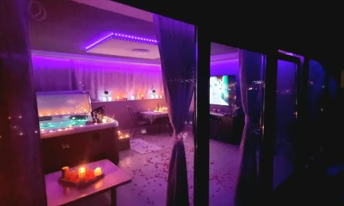 a room with purple lighting and a table with candles at Jacuzzi Home in Oradea