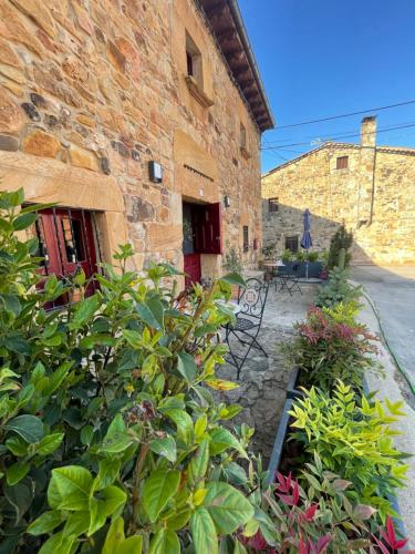 Casa Rural Zirimiri en Herreros, Soria في Herreros: مبنى امامه مجموعه من النباتات