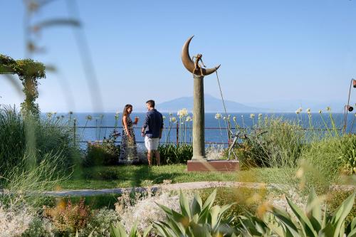 Un uomo e una donna in piedi accanto alla statua di un uccello. di Villa Marina Capri Hotel & Spa a Capri