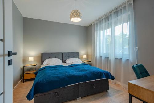 a bedroom with a blue bed and a window at Apartament Widok in Piechowice