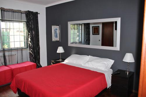 1 dormitorio con cama roja y espejo en Hostel Casa Lucas, en Charneca