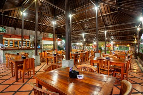 an empty restaurant with wooden tables and chairs at Nick's Pension in Ubud