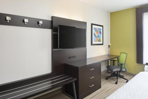 a hotel room with a tv and a desk and a bed at Holiday Inn Express Hotel & Suites Port Richey by IHG in Port Richey