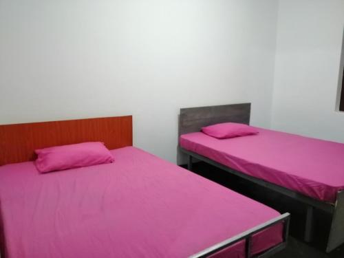 two beds in a room with pink sheets at Udara's Colombo Rooms in Battaramulla