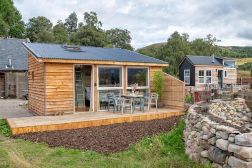 a tiny house with a deck and a table at Alba - Charming boutique forest view cabin with hot tub in Ballater in Ballater