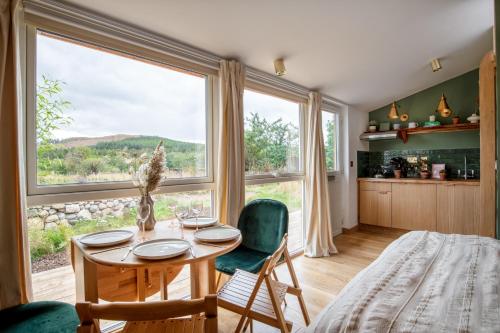 a dining room with a table and a large window at Alba - Charming boutique forest view cabin with hot tub in Ballater in Ballater