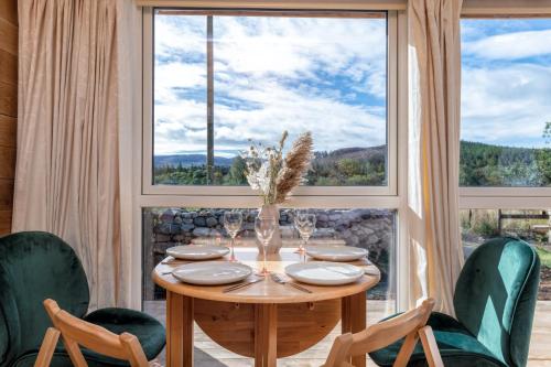 a dining room with a table and chairs and a large window at Alba - Charming boutique forest view cabin with hot tub in Ballater in Ballater