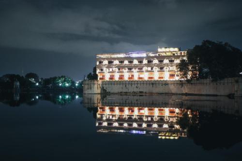 um edifício com o seu reflexo na água à noite em Rajdarshan - A Lake View Hotel in Udaipur em Udaipur