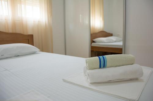 ein Bett mit zwei Handtüchern, die vor einem Spiegel darauf sitzen in der Unterkunft Apartments Milica in Becici